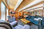 Experience cozy living in this charming cabin-style living room, featuring warm wood paneling and a vaulted ceiling with exposed beams.