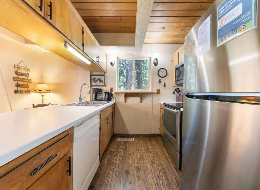 This charming kitchen features warm wooden cabinetry and a sleek white countertop, perfect for meal preparation.