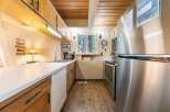 This charming kitchen features warm wooden cabinetry and a sleek white countertop, perfect for meal preparation.