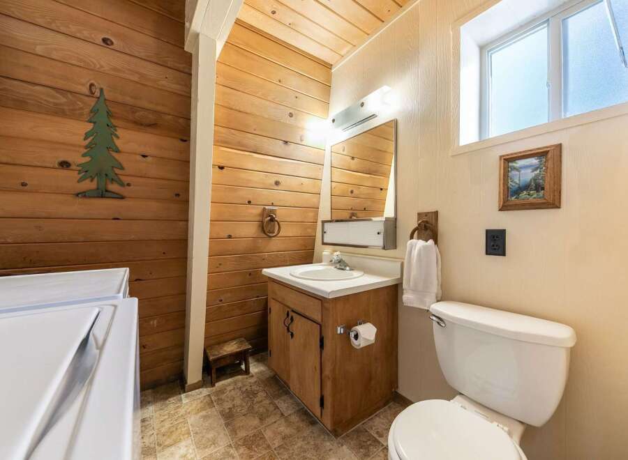 This rustic bathroom features warm wood paneling throughout, creating a cozy and inviting atmosphere.