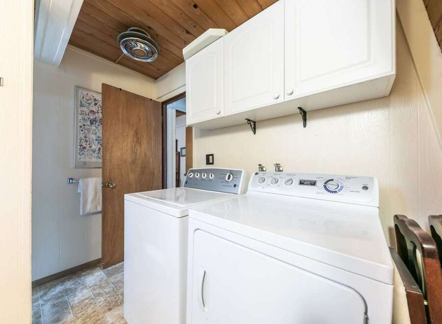 This laundry room features a white top-load washer and a white front-load dryer, perfect for handling all your laundry needs.