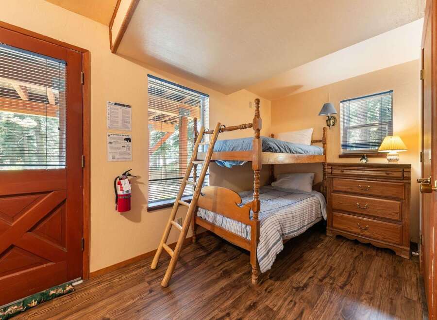 This cozy bedroom features a sturdy wooden bunk bed with blue bedding, perfect for accommodating guests or children.