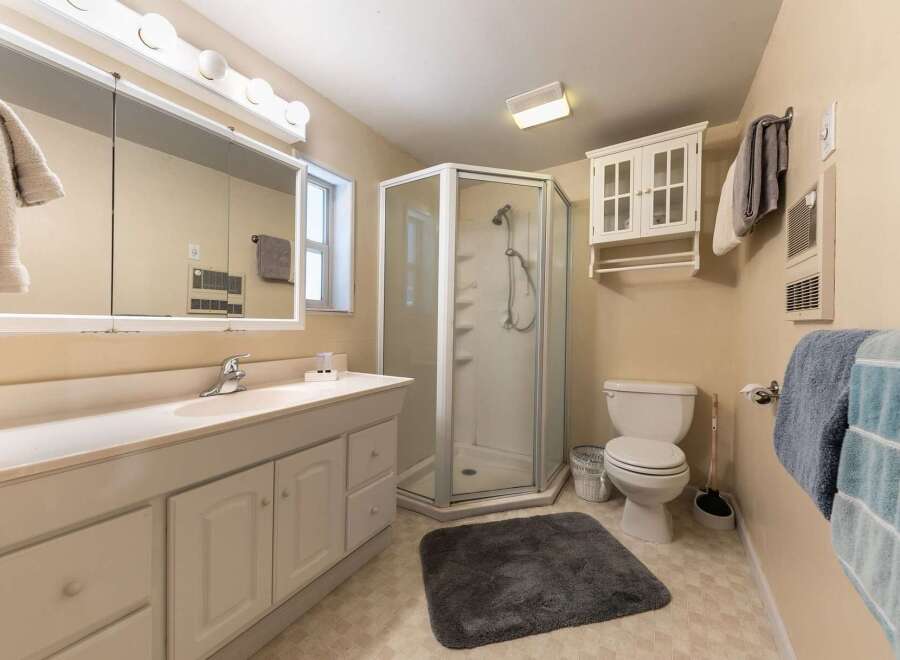 This bathroom features a spacious vanity with ample storage and a large mirror, perfect for your morning routine.