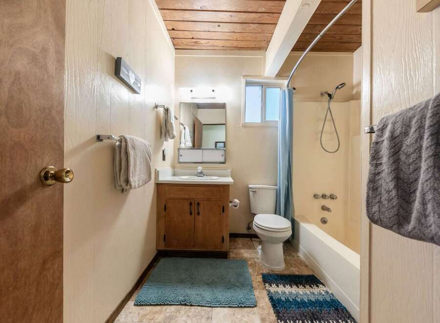 This charming bathroom features a wood-paneled ceiling and walls, creating a warm and inviting atmosphere.