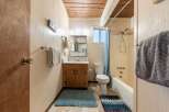 This charming bathroom features a wood-paneled ceiling and walls, creating a warm and inviting atmosphere.
