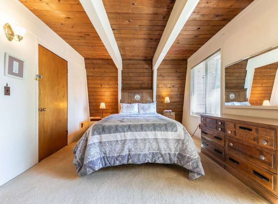 Experience cozy comfort in this charming bedroom, featuring a beautifully appointed queen-size bed with a patterned comforter and matching pillows.