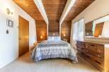 Experience cozy comfort in this charming bedroom, featuring a beautifully appointed queen-size bed with a patterned comforter and matching pillows.