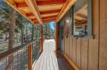 Experience rustic charm with this inviting cabin porch, featuring a spacious wooden deck and a covered roof supported by exposed beams.
