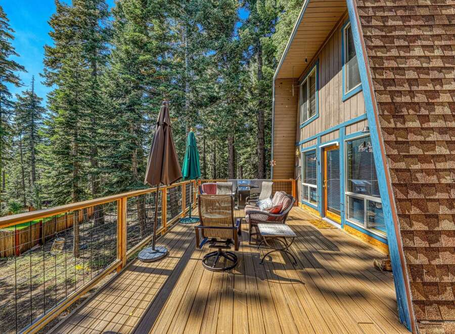 Enjoy outdoor living on this spacious wooden deck, perfect for entertaining or relaxing amidst a serene forest setting.