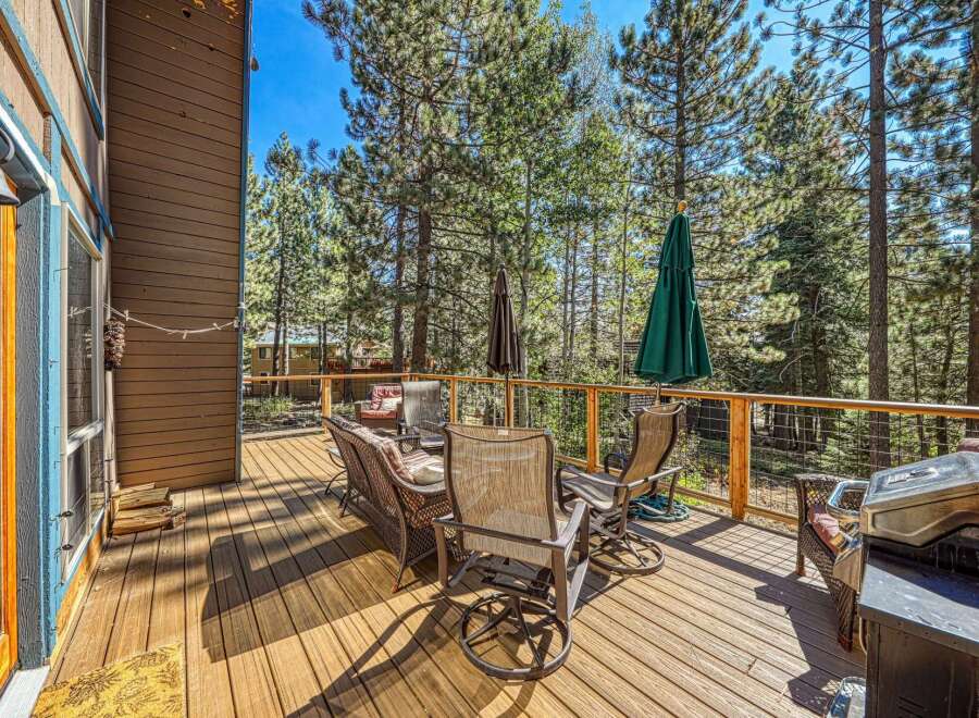Enjoy outdoor living on this spacious wooden deck, perfect for entertaining or relaxing amidst the tall pine trees.