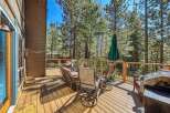 Enjoy outdoor living on this spacious wooden deck, perfect for entertaining or relaxing amidst the tall pine trees.