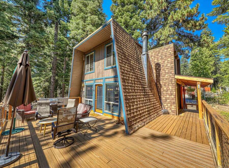 Enjoy outdoor living on this expansive wooden deck, perfect for entertaining or relaxing amidst the tall pine trees.
