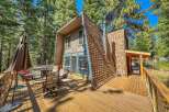 Enjoy outdoor living on this expansive wooden deck, perfect for entertaining or relaxing amidst the tall pine trees.