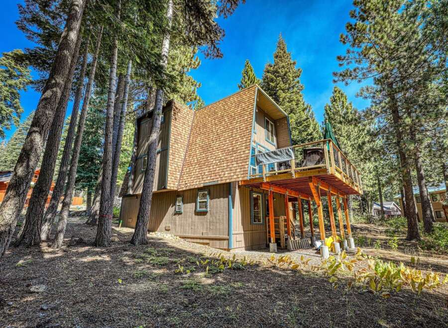 Nestled amongst tall pine trees, this charming A-frame cabin offers a serene mountain getaway.