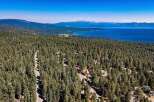 Discover this stunning aerial view showcasing a picturesque landscape with a dense forest of evergreen trees leading down to a serene blue lake.