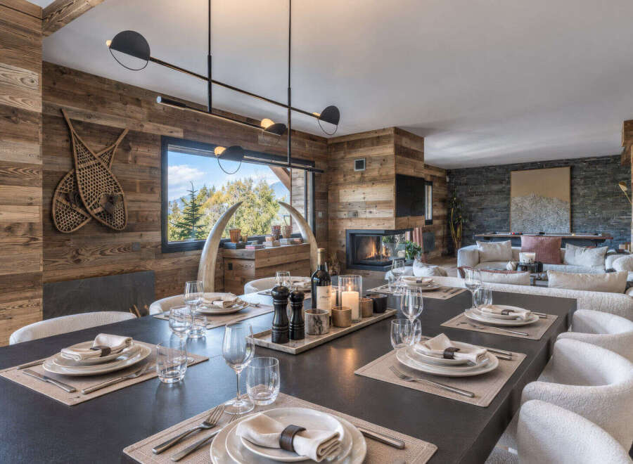 Experience luxurious mountain living in this stunning dining and living area, featuring a modern fireplace and panoramic windows with breathtaking forest views.