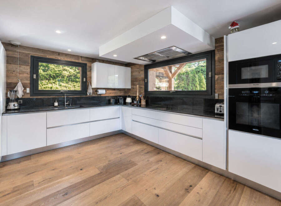 Experience modern luxury in this stunning kitchen, featuring sleek white cabinetry and a striking wood-paneled accent wall.