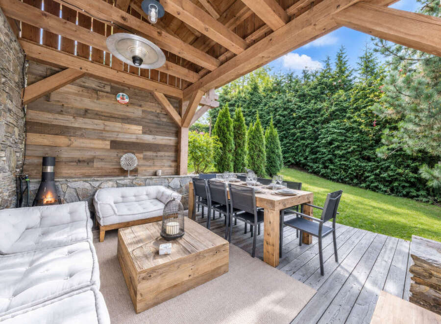 Experience luxurious outdoor living with this covered patio, featuring a cozy seating area with a fireplace and a spacious dining table perfect for entertaining.