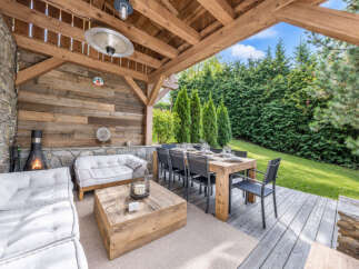 Experience luxurious outdoor living with this covered patio, featuring a cozy seating area with a fireplace and a spacious dining table perfect for entertaining.