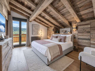 Experience rustic luxury in this charming mountain bedroom, featuring exposed wooden beams and a cozy plaid bedding set.