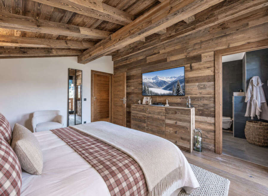 Experience rustic luxury in this charming bedroom, featuring a cozy bed adorned with plaid accents and a soft throw.