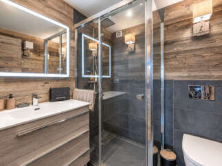 Experience luxury in this modern bathroom, featuring a sleek vanity with ample storage and a large, illuminated mirror.
