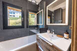 Experience modern comfort in this stylish bathroom, featuring a sleek bathtub and a spacious vanity with a large, illuminated mirror.
