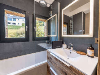 Experience modern comfort in this stylish bathroom, featuring a sleek bathtub and a spacious vanity with a large, illuminated mirror.