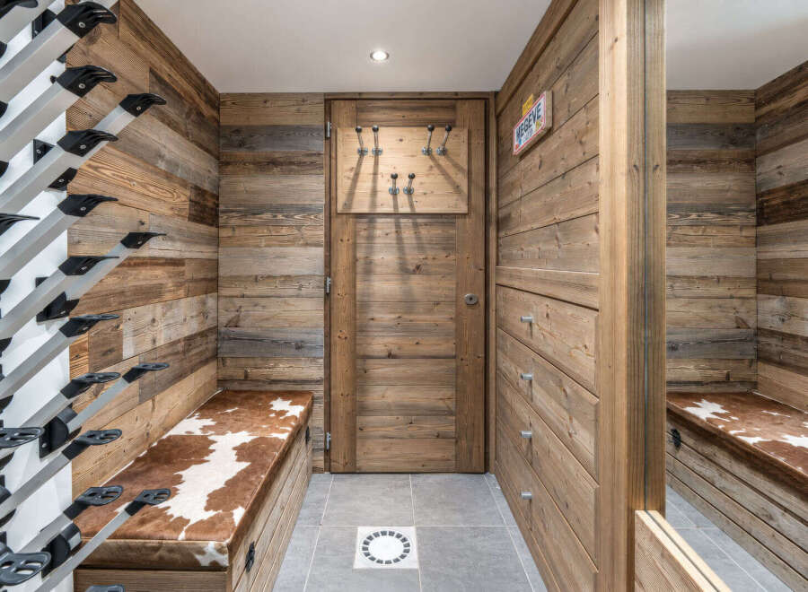 This ski room features a rustic wooden paneling and a practical ski boot rack system.