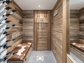 This ski room features a rustic wooden paneling and a practical ski boot rack system.