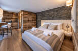Experience rustic luxury in this beautifully appointed bedroom featuring a cozy king-size bed with plush linens and decorative pillows.