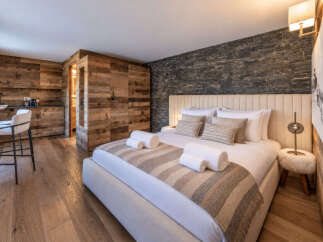 Experience rustic luxury in this beautifully appointed bedroom featuring a cozy king-size bed with plush linens and decorative pillows.