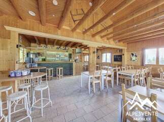 Step into this charming mountain restaurant, featuring a rustic wooden interior with exposed beams and a cozy bar area.