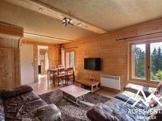 Experience cozy living in this charming wooden cabin, featuring a comfortable living area with plush leather sofas and a rustic dining space.