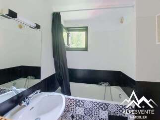 This bathroom features a bathtub with a black shower curtain and a small window, offering a clean and functional space.