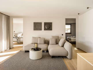 Experience modern living in this spacious apartment, featuring a comfortable living area with a plush sectional sofa and a stylish coffee table adorned with candles.