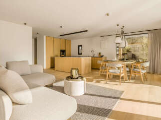 Experience modern living in this open-concept space, featuring a sleek, light wood kitchen with integrated appliances and a spacious island.