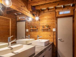 Experience rustic charm in this bathroom featuring a double vanity with modern rectangular sinks and sleek chrome faucets.