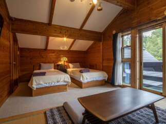 Experience rustic charm in this cozy wooden cabin bedroom, featuring two comfortable twin beds perfect for a relaxing getaway.