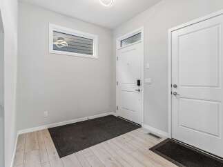 Step into a bright and welcoming entryway featuring a modern white door with a sleek digital lock and a transom window for natural light.