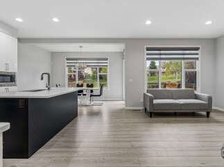 Experience modern living in this open-concept home featuring a sleek kitchen island with a waterfall countertop and a stylish dark base.