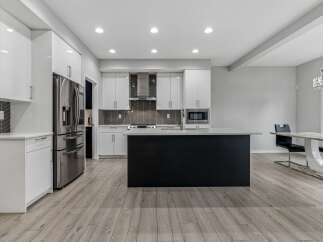 Experience modern living in this stunning kitchen featuring sleek white cabinetry and a striking black island.