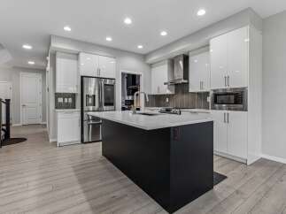 Experience modern living in this stunning kitchen featuring sleek white cabinetry and a striking dark island.
