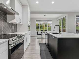 Experience modern luxury in this stunning kitchen, featuring sleek white cabinetry, a striking herringbone tile backsplash, and a spacious island with a contemporary faucet.