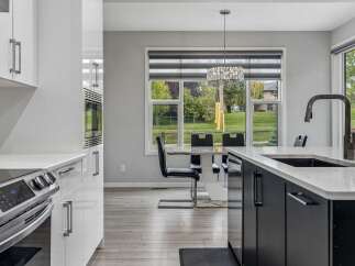Experience modern living in this stunning kitchen featuring sleek white cabinetry, a built-in microwave, and a stainless steel range.