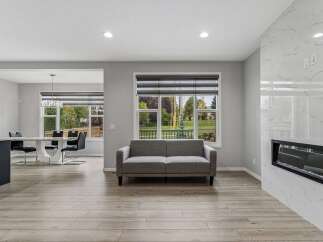 Experience modern living in this open-concept home featuring a sleek dining area with a striking white pedestal table and black chairs, complemented by a crystal chandelier.