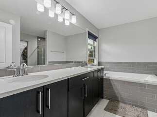 This modern bathroom features a sleek double vanity with dark cabinetry and a white quartz countertop, complemented by chrome fixtures.