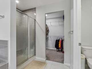 Step into this spacious bathroom featuring a sleek glass-enclosed shower with modern gray tile accents.