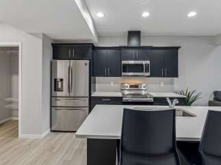 Discover this modern kitchen featuring sleek dark cabinetry, stainless steel appliances including a French door refrigerator and a built-in microwave.