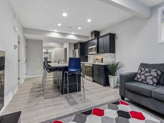 This modern open-concept living space features a sleek dark-cabinet kitchen with stainless steel appliances and a large island with bar seating.